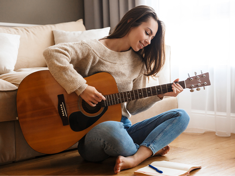 Woman playing guitar - for Bupa web article on 10 ways to be kind to yourself