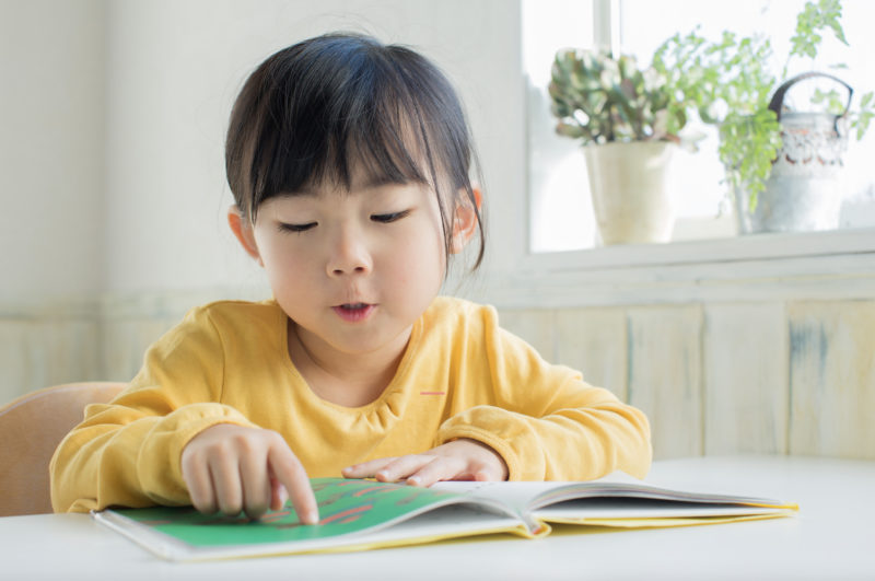 Child reading for web article on helping children struggling to read with phonics and reading 